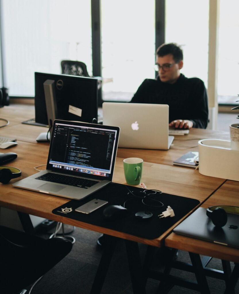 Man in Black Shirt Sits Behind Desk With Computers